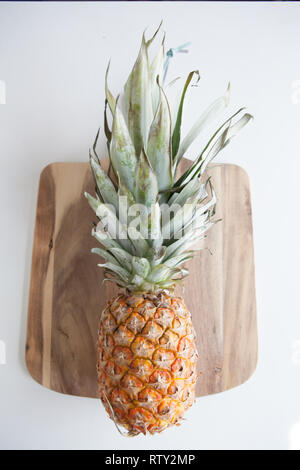 Eine Ananas in einem flach Layout auf einer hölzernen Schneidebrett Stockfoto