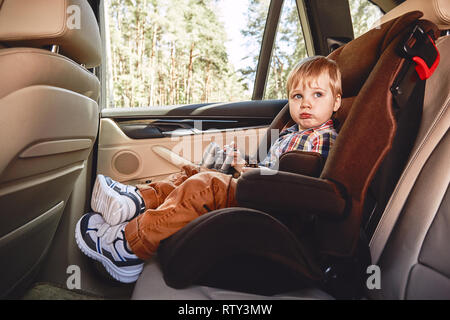 Adorable Baby Boy ist Spielen mit Spielzeug Fernglas und Halten der Pinecone während der Sitzung in Safety Car Seat. Seitenansicht Stockfoto