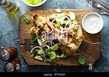 Huhn Kebabs auf ein Fladenbrot mit Gemüse und Oliven, griechischen Mittagessen inspiriert Overhead shot Stockfoto