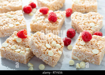 Herz- und quadratische Rice crispy Marshmallow behandelt mit weißer Schokolade und Himbeeren Stockfoto