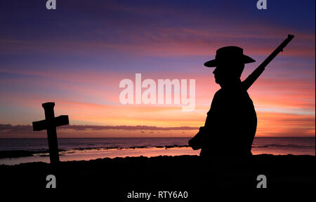 Die Silhouette eines australischen Soldaten im Ersten Weltkrieg AIF einheitliche und 303 Gewehr mit Kreuz bei Sonnenaufgang in der Nähe des Strandes mit Platz kopieren Stockfoto