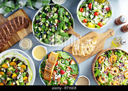 Verschiedene Salate mit frischen Zutaten auf den Tisch mit gegrillten Steaks, Huhn Brest und Lachs, sauber essen Konzept Stockfoto
