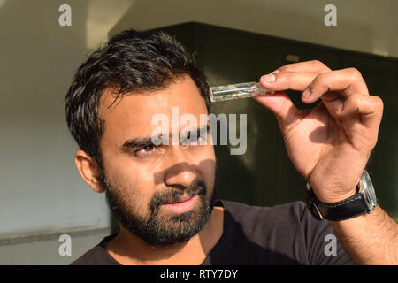 Junger Mann entomologe Beobachtung Insekten in Glas vile und versuchen, es für seine Insekt Probenentnahme während einer hellen Sommer zu identifizieren. Stockfoto