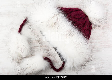 Rot gestrickt Winter hut mit Pelz auf weißem Holz- Hintergrund. Stockfoto