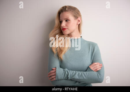 Die Hälfte Profil Aufnahme der schöne junge Frau mit blonden langen Haaren auf hellgrauem Hintergrund. Stockfoto