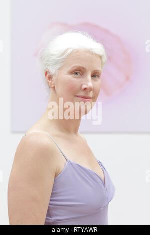 Porträt eines schönen und selbstbewussten älteren Frau mit weißen Haaren in ärmelloses top vor Rosa Hintergrund. Stockfoto