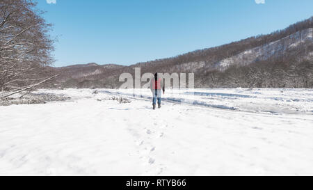 Ein einsamer Mann Spaziergänge entlang der gefrorenen Bett von einem mountain river Stockfoto