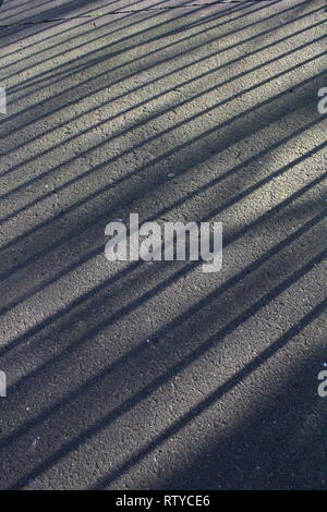 Schatten von geländern auf einem Fußweg in Großbritannien Stockfoto