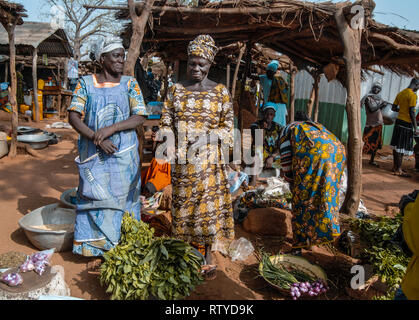 Ein nettes Foto von zwei schönen Ghanaische Frauen tragen traditionelle Kleidung verkaufen Gemüse und Gewürze auf dem lokalen Markt für frische im Kongo Dorf. Stockfoto