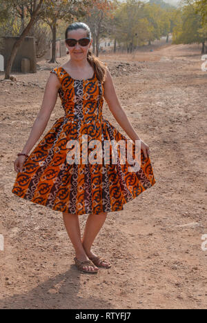 Eine schöne kaukasische Frau für eine Kamera in ein schönes Kleid von lokalen ghanaischen Stoff in eine Savanne in Ghana, Westafrika, posing Stockfoto