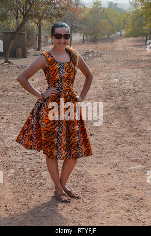 Eine schöne kaukasische Frau für eine Kamera in ein schönes Kleid von lokalen ghanaischen Stoff in eine Savanne in Ghana, Westafrika, posing Stockfoto