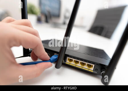 Man verbindet das Internet Kabel an die Buchse des Routers. Schnelle und kabellose Internet Konzept Stockfoto