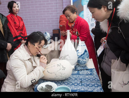 Huzhou, der chinesischen Provinz Zhejiang. 3 Mär, 2019. Die Menschen sehen eine handwerkerin malen ein Halbzeug Porzellan an gucheng Dorf Daochang Township in Huzhou Stadt, im Osten der chinesischen Provinz Zhejiang, 3. März 2019. Eine Kultur und Tourismus Fall wurde an gucheng Dorf statt und zieht viele Touristen Volkskultur zu erleben. Credit: Weng Xinyang/Xinhua/Alamy leben Nachrichten Stockfoto