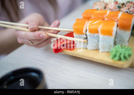 Mädchen essen Sushi mit Stäbchen auf Restaurant. Nach oben Schließen Stockfoto