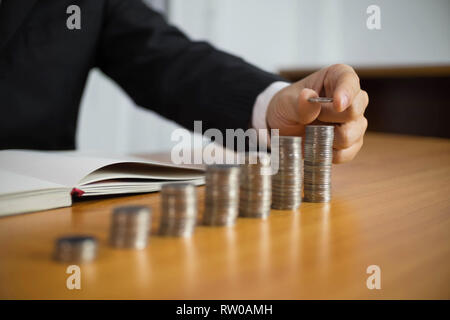 Geschäftsmann nimmt Münzen auf den Tisch und zählt Geld. Geschäftskonzept. Stockfoto