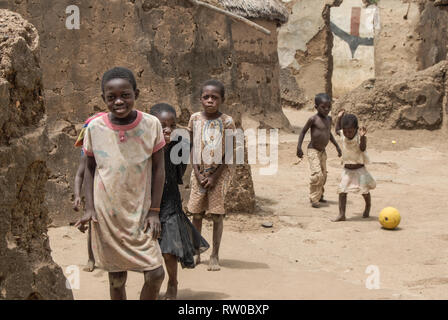 Ein ästhetisches Foto der schönen Happy ghanaische Kinder für ein Foto posiert während Fußball spielen auf einem lokalen schmutzigen und staubigen Straße. Stockfoto