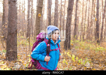 Leute, Wandern und Natur Konzept - Frau gekleidet in blaue Jacke Wandern in den Wald Stockfoto