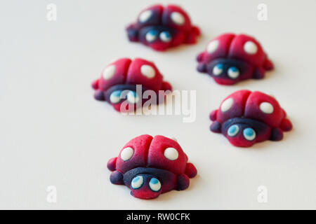 Gruppe von roten Marienkäfer mit blauen Augen und weißen Punkten aus süßen Zucker Stockfoto