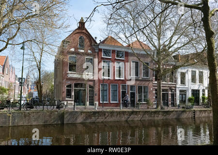 Niederlande, Gouda, 2017, Radfahrer vorbei vor der traditionellen Häuser am Ufer eines canel. Stockfoto