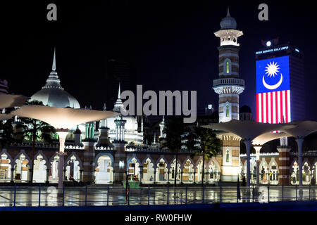 Masjid Jamek (Jamek Moschee) in der Nacht, malaysischer Flagge im Hintergrund. Kuala Lumpur, Malaysia. Stockfoto