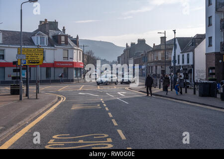 Largs, Schottland, Großbritannien - 19 Februar 2019: Besetzt Largs Stadtzentrum an einem ungewöhnlich warmen Tag für Februar 16-18°C mit fliessenden Verkehr an der Hauptstraße. Stockfoto