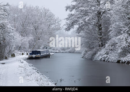 Kanal Boot vertäut am Kanal in der Nähe von Macclesfield Bollington im Winter. Die Bäume und leinpfad sind mit Schnee bedeckt Stockfoto