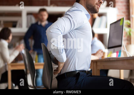 Geschäftsmann leidet unter Schmerzen im unteren Rücken sitzen in Shared Office Stockfoto