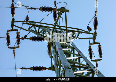 Blick vom Boden bis zum strommast Top. Kabel und keramischen Isolatoren sichtbar gegen den blauen Himmel. Abstract Power Industry Hintergrund. Stockfoto