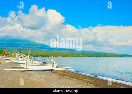 Sonnenschein Wetter am Strand mit traditionellen Fischerbooten, Agung Vulkan in Wolken im Hintergrund, Bali, Indonesien Stockfoto