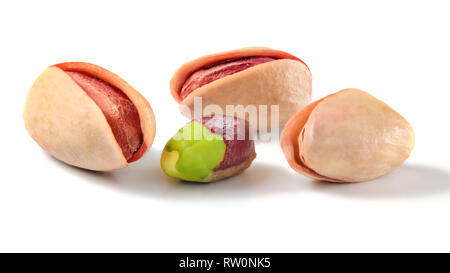 Drei Türkischen Roten Pistazien, geröstet und eines teilweise geschält grüne Mutter auf weißem Hintergrund Stockfoto