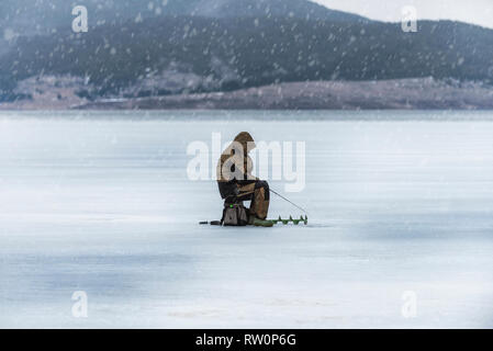 Eis Fischer auf gefrorenen winter Mountain Lake Batak in Bulgarien während der letzten Tage des Winters 02.03.2019 Stockfoto