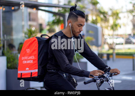 Lima, Peru - 3. März 2019: Gut aussehenden Mann reiten Fahrrad arbeiten für Rappi Lebensmittel Lieferservice, Kontrolle der App auf sein Smartphone. Sharing sonderfor Stockfoto