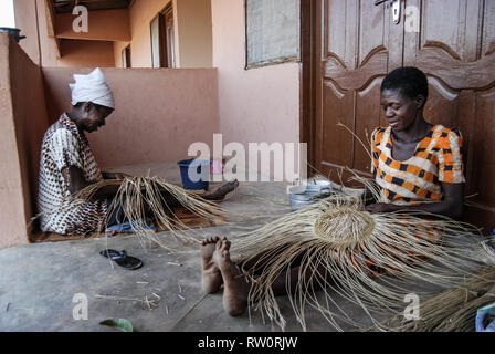 Ein Foto von zwei lokalen Ghanaische Frauen weben der berühmten bolga (bolgatanga) Handgewebte markt Körbe an ihrem Haus in Kongo, Ghana. Stockfoto