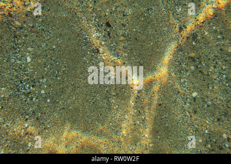 Unterwasser Foto, seichten Meer untere Etage von oben gesehen, Lichtbrechung Regenbogen, Blicke auf Sand. Abstrakte marine Hintergrund. Stockfoto