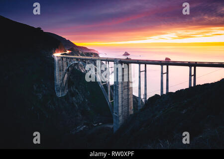 Bixby Creek Bridge mit bunten Sonnenuntergang und Auto leichte Wanderwege, Big Sur, CA Stockfoto