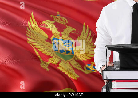 Erfolgreiche Montenegrinischen studentische Ausbildung Konzept. Holding Bücher und skalenhaube über Montenegro Flagge Hintergrund. Stockfoto