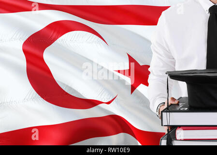 Erfolgreiche Türkische studentische Ausbildung Konzept. Holding Bücher und skalenhaube über das nördliche Zypern Flagge Hintergrund. Stockfoto