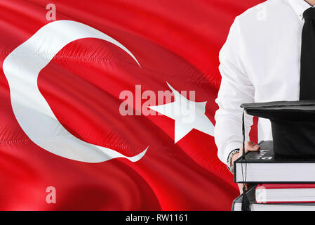 Erfolgreiche Türkische studentische Ausbildung Konzept. Holding Bücher und skalenhaube über der Türkei Flagge Hintergrund. Stockfoto