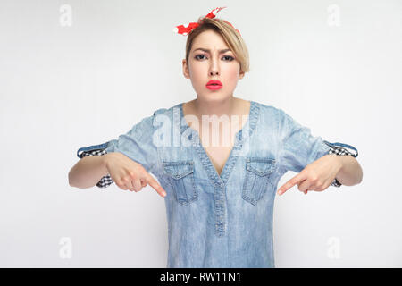 Hier und Jetzt. Portrait von schweren Bossy schöne junge Frau in lässigem Blue Denim Shirt mit roten Stirnband ständigen Blick auf Kamera und pointi Stockfoto