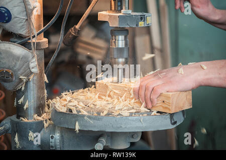 Die Zimmerleute mit elektrischen Bohrmaschine bohren Holzbrett Stockfoto