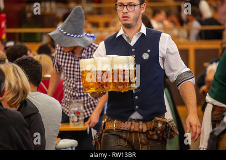 Oktober 7, 2018. München, Deutschland, Oktoberfest, Kellner in Tiroler Tracht holding Biere, Zelt innen Hintergrund Stockfoto