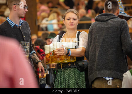 Oktober 7, 2018. München, Deutschland, Oktoberfest, Kellnerin in Tiroler Tracht holding Biere, Zelt innen Hintergrund Stockfoto