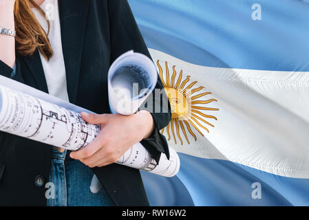 Argentinischen Architekten Frau mit Blueprint gegen Argentinien wehende Flagge Hintergrund. Bau und Architektur Konzept. Stockfoto