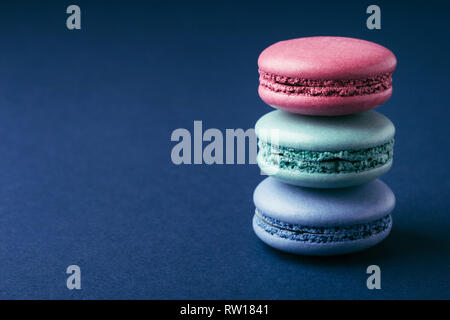 Stapel von drei bunte Macarons auf dunkelblauem Hintergrund mit kopieren. Stockfoto