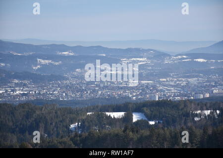 Kärnten, Villach, Stadt, Panorama, Skyline, Stadt, Dobratsch, Wegkreuz, Holzkreuz, Baum, Wald, Winter, Schnee, Wiese, Weide, verschneit, kahl, Ast, als Stockfoto