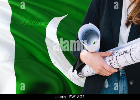 Pakistanische Architekt Frau mit Blueprint gegen Pakistan wehende Flagge Hintergrund. Bau und Architektur Konzept. Stockfoto