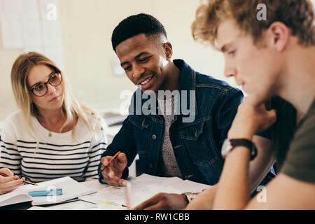 Afrikanischen jungen Lernen mit Klassenkameraden. Gruppe von multi-ethnischen Schüler arbeiten an der Hochschule Aufgaben in Campus. Stockfoto