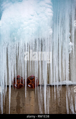 Große Eiszapfen hängen über Wasser Ventile Stockfoto