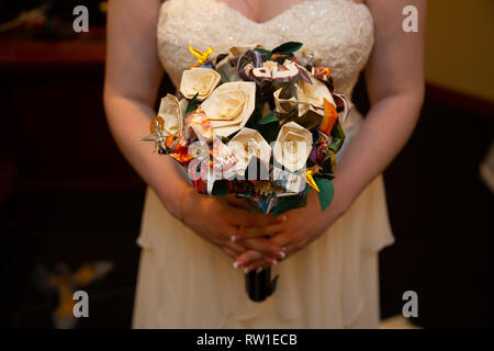 Braut holding Blumenstrauß vor sich am Hochzeitstag Stockfoto