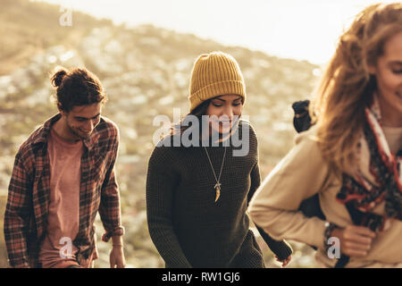 Frau Klettern ein Hügel mit Freunden. Gruppe von Männern und Frauen gemeinsam wandern. Stockfoto